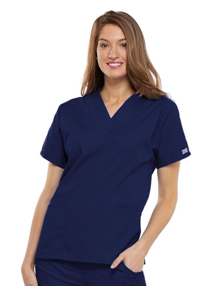 A young female LPN wearing a Cherokee Workwear Originals Women's V-neck Scrub Top in Navy size 2XL featuring short sleeves.