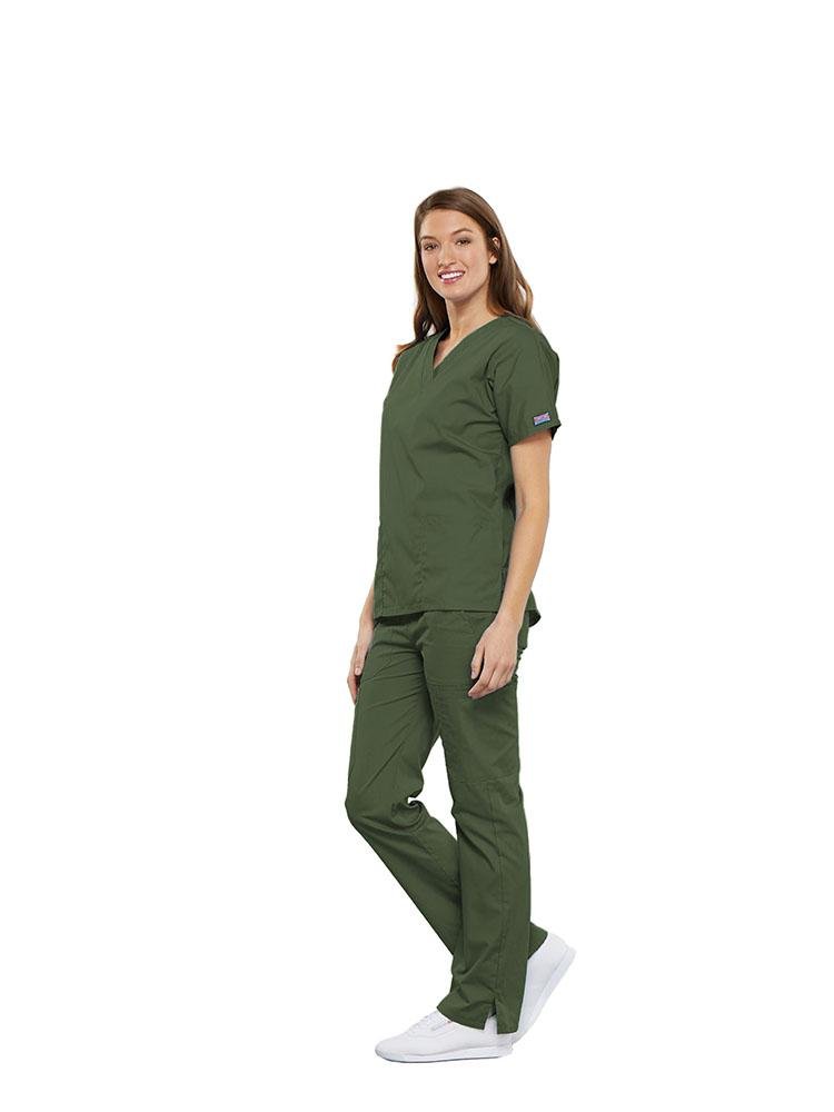 A female Clinical Laboratory Technologist wearing a Cherokee Workwear Originals women's Multi-Pocketed V-Neck Scrub Top in Olive size Large featuring side seam vents for additional range of motion throughout the day.