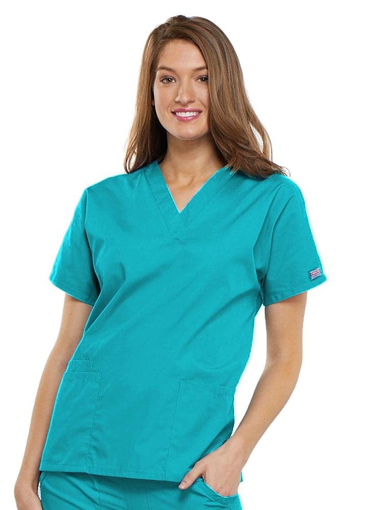 A young female LPN wearing a Cherokee Workwear Originals Women's V-neck Scrub Top in Turquoise size 2XL featuring short sleeves.