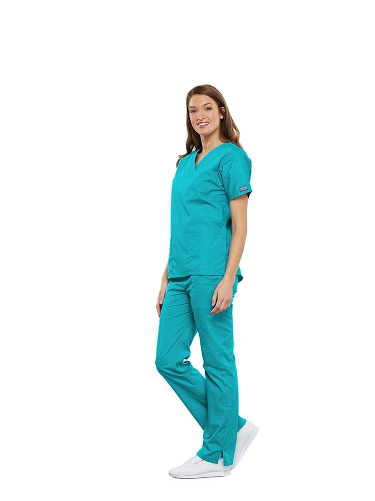 A female Clinical Laboratory Technologist wearing a Cherokee Workwear Originals women's Multi-Pocketed V-Neck Scrub Top in Turquoise size medium featuring side seam vents for additional range of motion throughout the day.