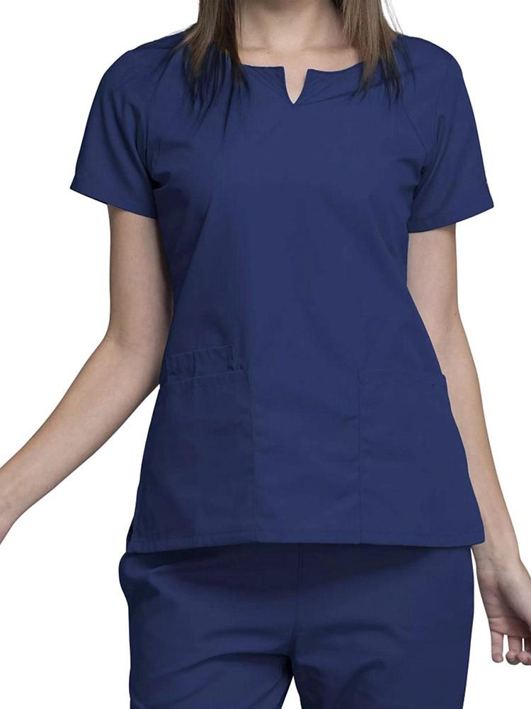 A young female Dental Assistant wearing a Cherokee Workwear Originals Women's Notch Crew Neck Scrub Top in Navy size 2XL featuring a round neckline and curved front neck yokes.