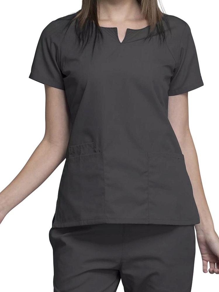 A young female Medical Assistant wearing a Cherokee Workwear Originals Women's Notch Crew Neck Scrub Top in Pewter size 2XL featuring a round neckline and curved front neck yokes.