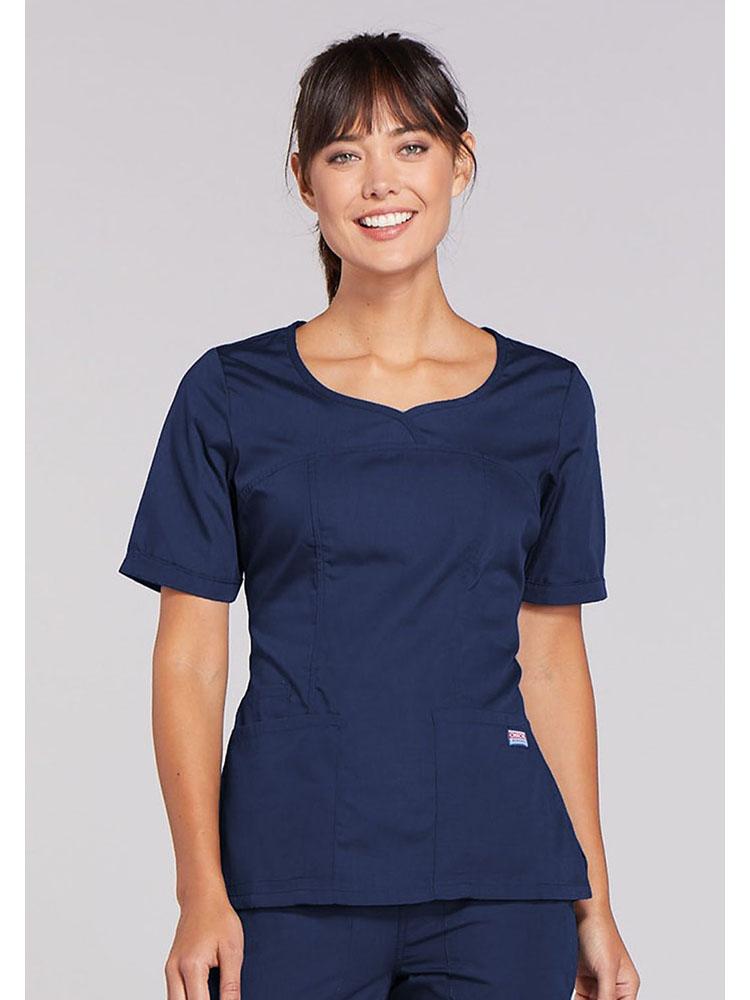 A young female Occupational Therapist wearing a Cherokee Workwear Original's Women's Novelty Crossed V-neckline Scrub Top in Navy size 2XL.