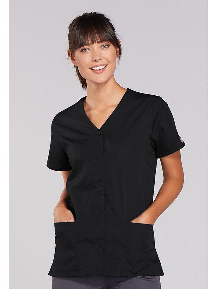 A young female Nurse Practitioner wearing a Cherokee Workwear Originals Women's Snap Front Scrub Top in Black size 4XL featuring 2 front patch pockets.