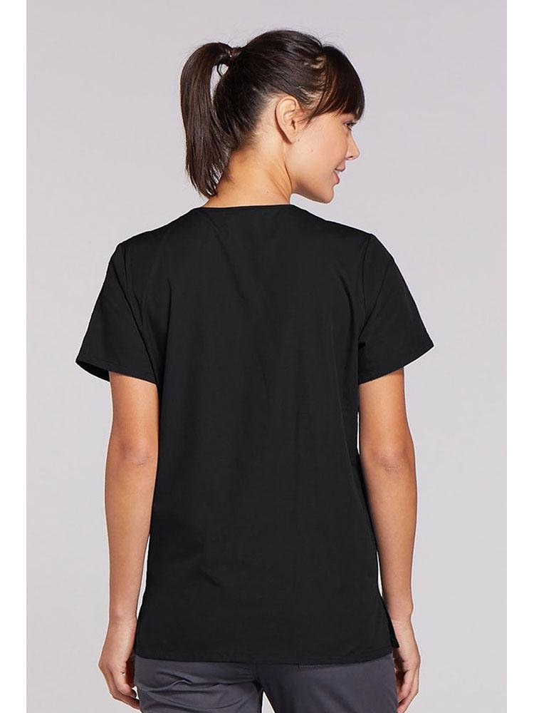 A young female Physician's Assistant wearing a Cherokee Workwear Originals Women's Snap Front Scrub Top in Black size Medium featuring a center back length of 26.5".