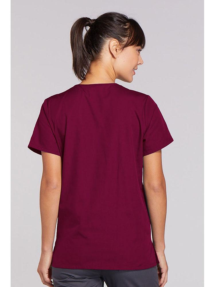 A young female Physician's Assistant wearing a Cherokee Workwear Originals Women's Snap Front Scrub Top in Wine size Medium featuring a center back length of 26.5".