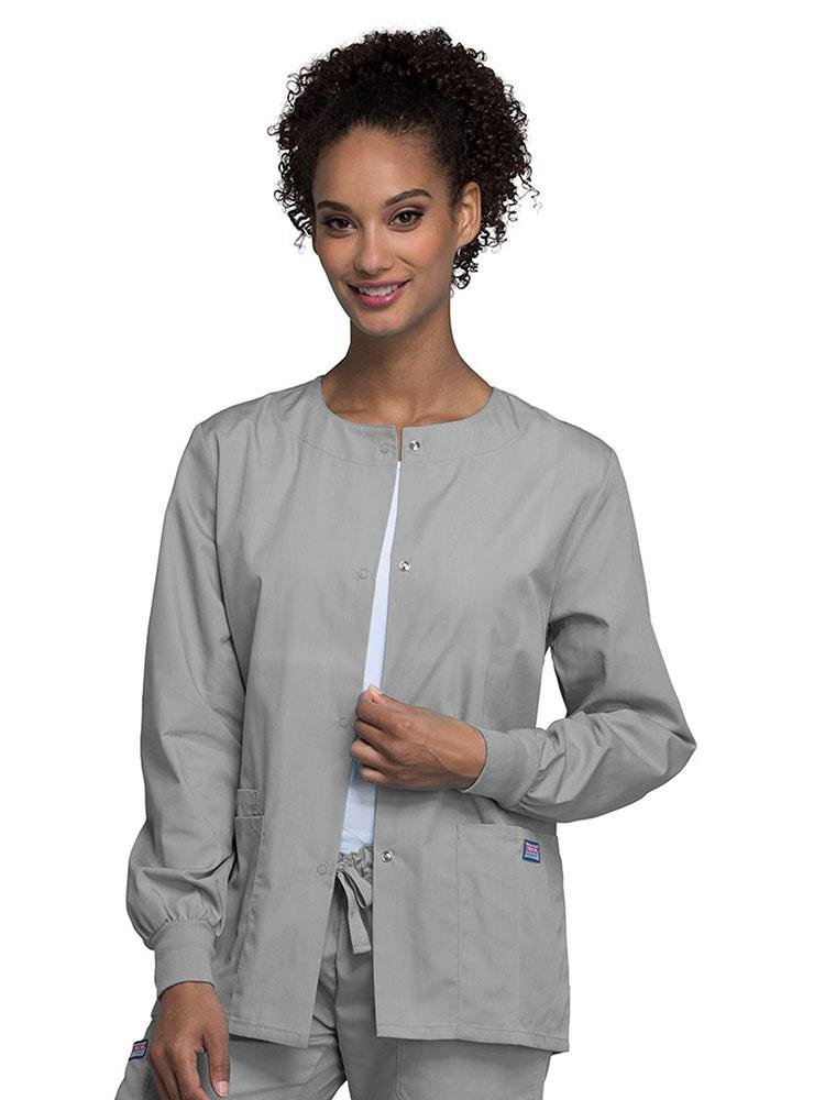 A young female LPN wearing a Cherokee Workwear Originals Women's Snap Front Warm-Up Jacket in Grey featuring a Traditional Classic fit & a round neck.
