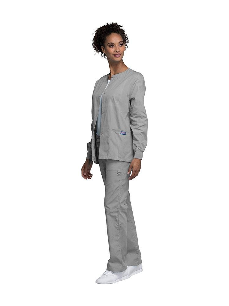 A female Dermatologist wearing a Cherokee Workwear Originals women's Snap Front Warm-Up Jacket in grey size extra large.