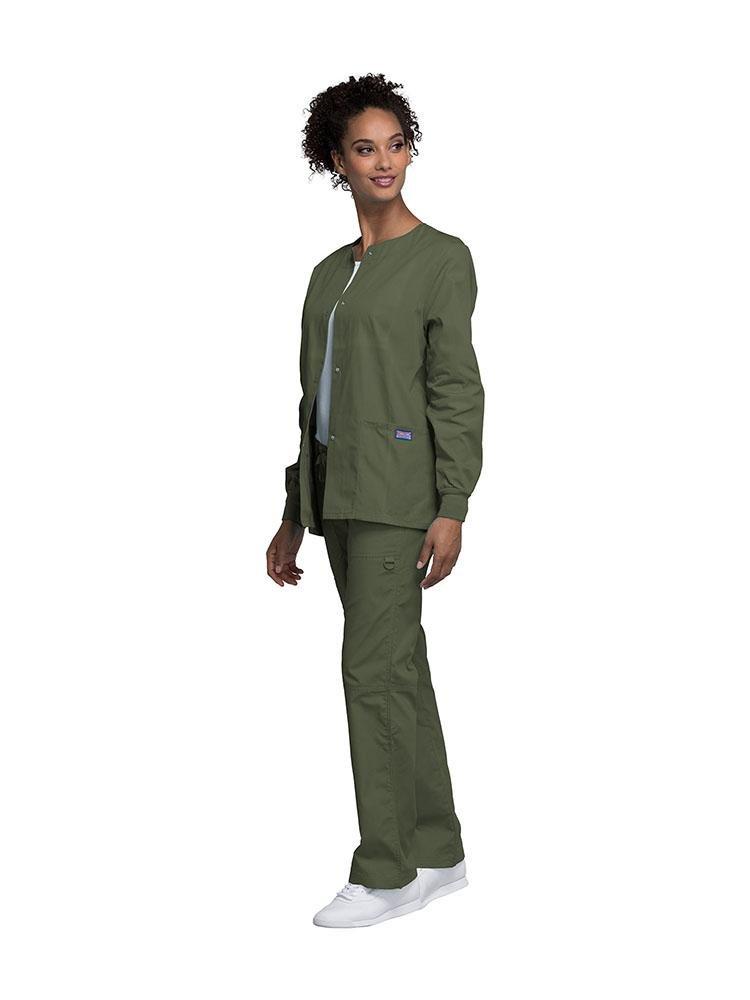 A young female LPN wearing a Cherokee Workwear Originals Women's Snap Front Warm-Up Jacket in Olive featuring A Traditional Classic fit & a round neck.