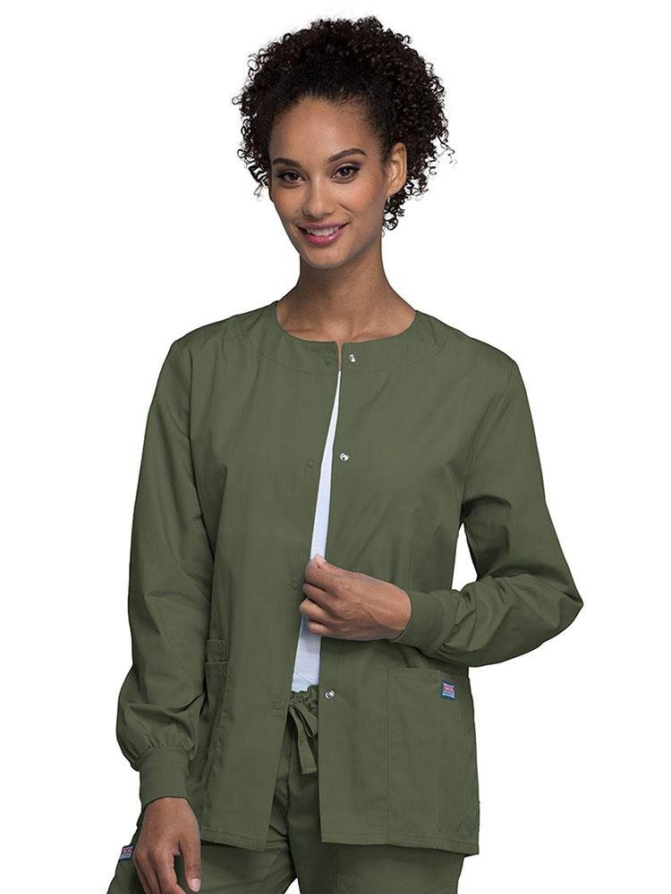 A young female Medical Secretary wearing Cherokee Workwear Originals women's Snap Front Warm-Up Jacket in Olive size extra small featuring knit cuffs to provide a flattering all day fit.