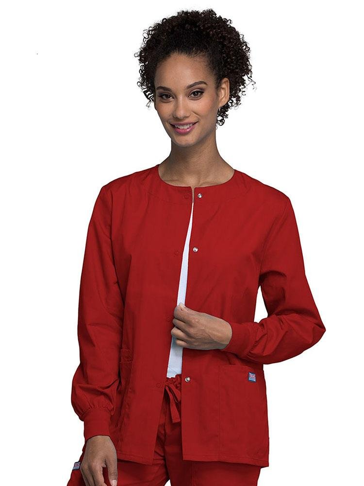A young female LPN wearing a Cherokee Workwear Originals Women's Snap Front Warm-Up Jacket in Red size Medium featuring A Traditional Classic fit & a round neck.