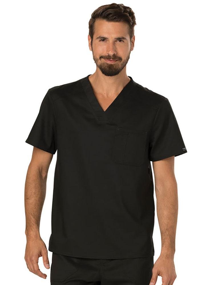 A young male Physician's Assistant wearing a Cherokee Workwear Revolution Men's Single Pocket V-neck Scrub Top in Black size 2XL featuring a single chest pocket on the wearer's left side.