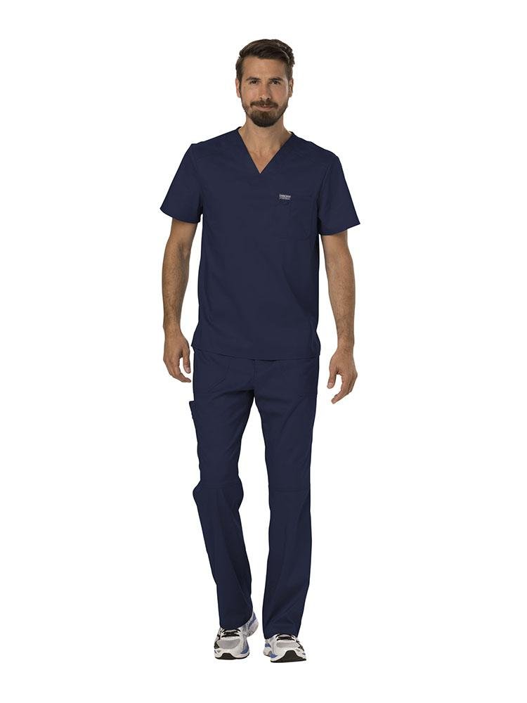 A young male MRI Technician wearing a Cherokee Workwear Revolution Men's Single Pocket V-neck Scrub Top in Black size Small featuring a v-neckline & short sleeves.