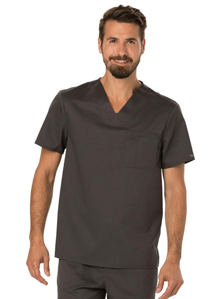 A young male Physical Therapist wearing a Cherokee Workwear Revolution Men's Single Pocket V-neck Scrub Top in Pewter size 2XL featuring a single chest pocket on the wearer's left side.