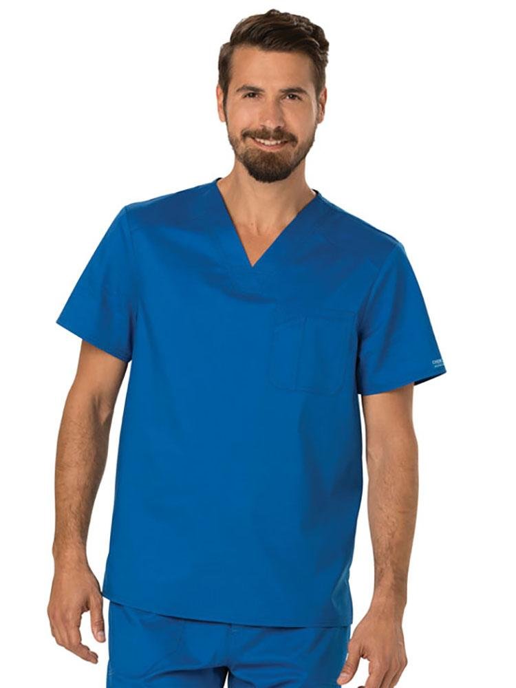 A young male Registered Nurse wearing a Cherokee Workwear Revolution Men's Single Pocket V-neck Scrub Top in Royal Blue size 2XL featuring a single chest pocket on the wearer's left side.