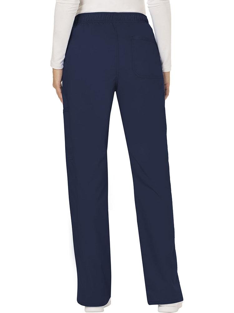 A female Physician wearing a Cherokee Workwear Revolution Women's Mid Rise Moderate Flare Scrub Pant in Navy size Medium Tall featuring a back patch pocket for additional storage space.