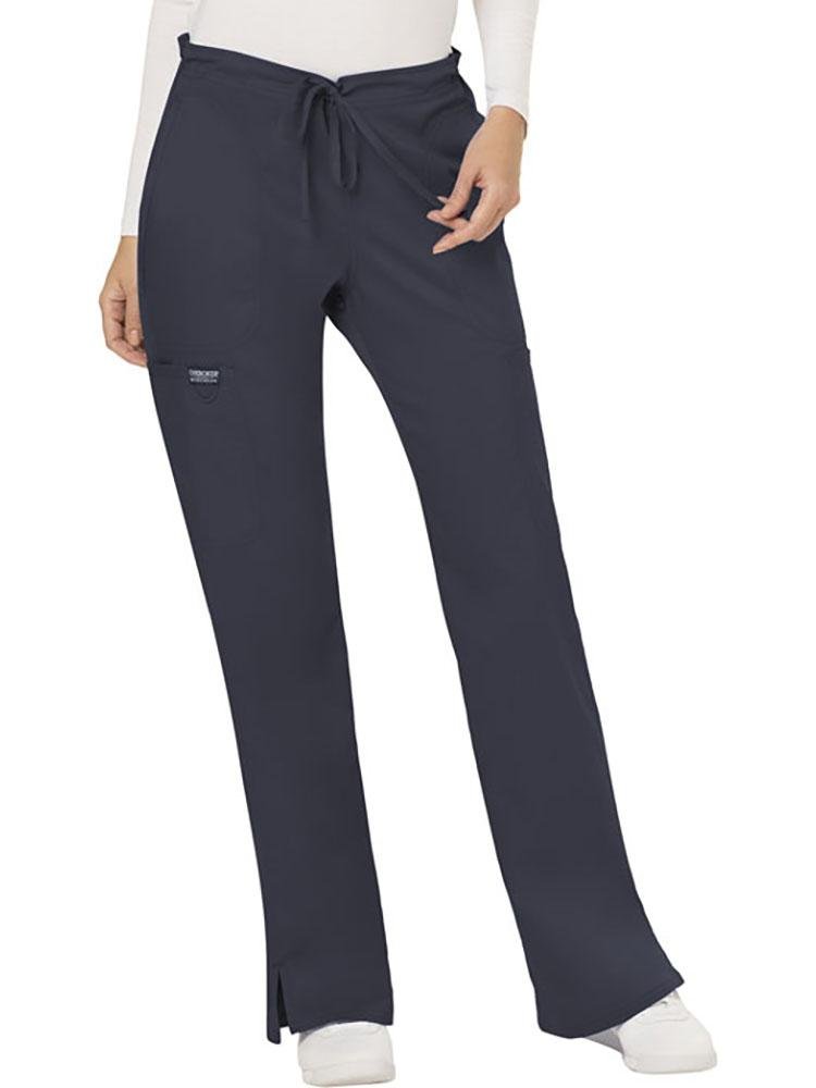 A young female Occupational Therapy Aide  wearing a Cherokee Workwear Revolution Women's Mid Rise Moderate Flare Scrub Pant in Pewter size XL Petite featuring a drawstring waist to provide a flattering & comfortable all day fit.