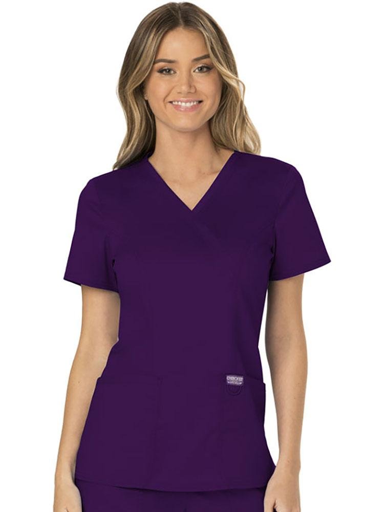 A female Phlebotomist wearing a Cherokee Workwear Revolution Women's Mock Wrap Scrub Top in eggplant size 2X featuring 2 front patch pockets for your on the job storage needs.