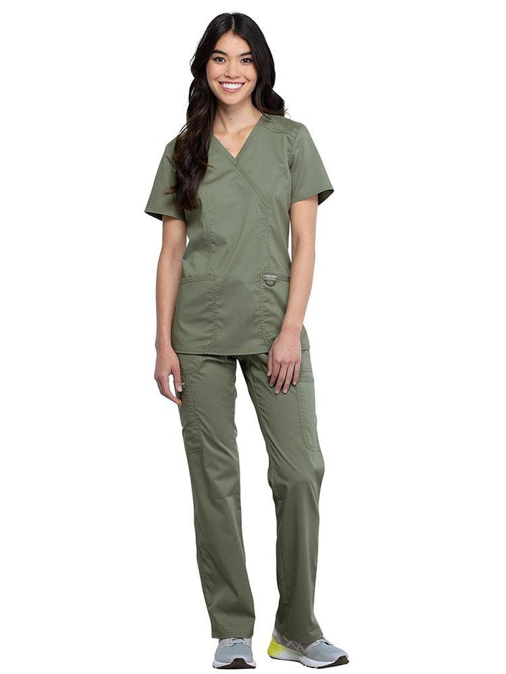 LPN wearing Cherokee Workwear Revolution women's Mock Wrap Scrub Top & Elastic Waist Scrub Pant in olive size small