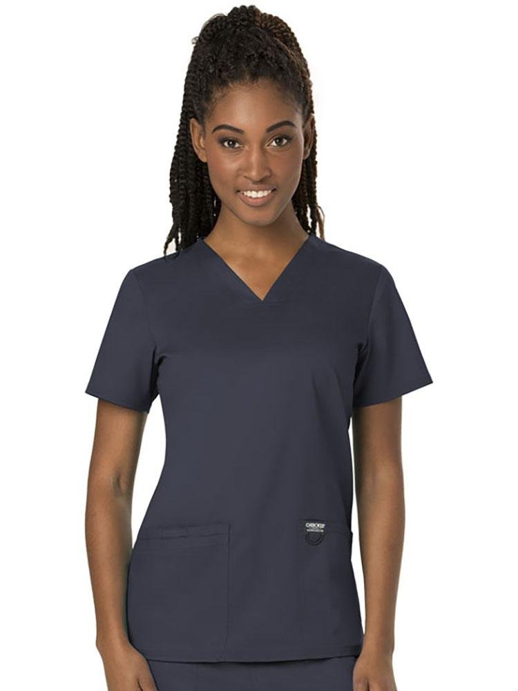 A young female Dental Hygienist wearing a Cherokee Women's Revolution Women's V-neck Scrub Top in Pewter size Medium featuring 2 front pockets for you on the job storage needs.