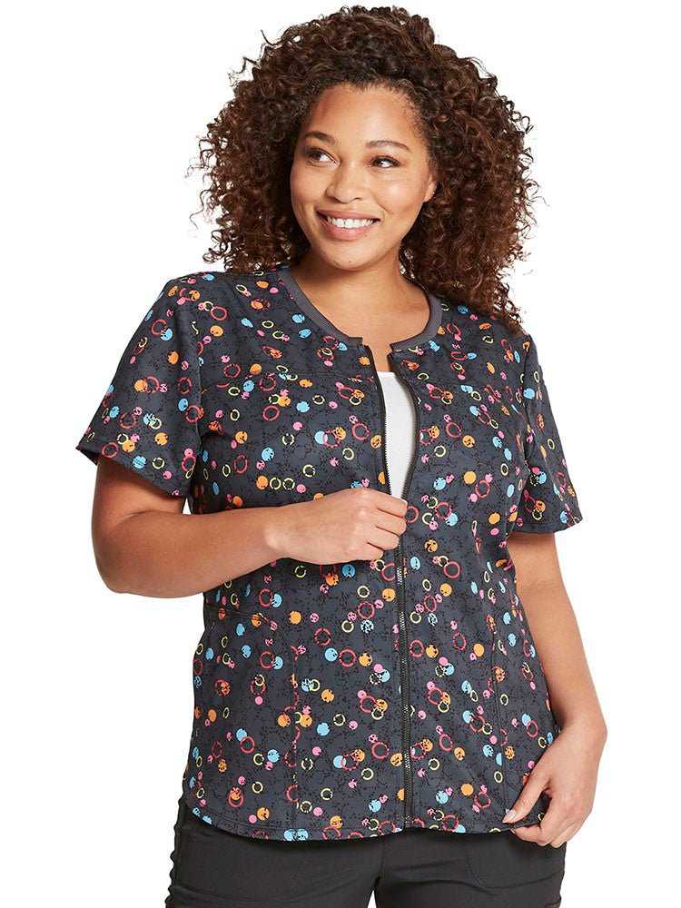 Young nurse wearing a Dickies Women's Zip-up Top  in Dot's So Bright featuring  3 pockets & a shirttail hem to ensure a flattering all day look. 
