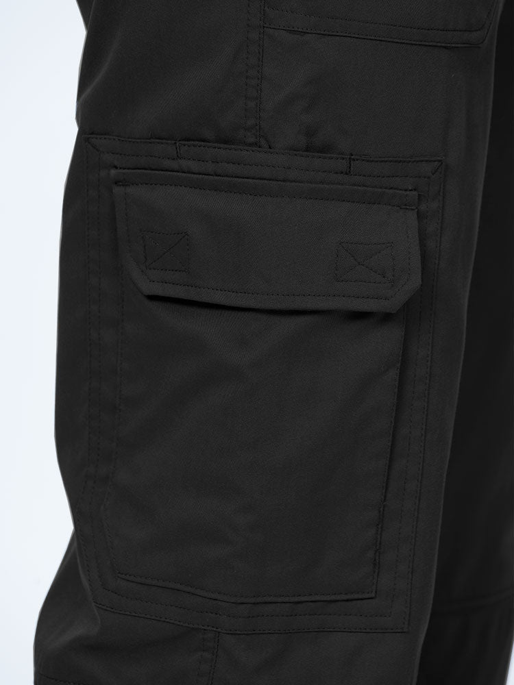 Man wearing an Epic by MedWorks Men's Button Front Scrub Pant in black with 1 double cargo pocket on wearer's right side.