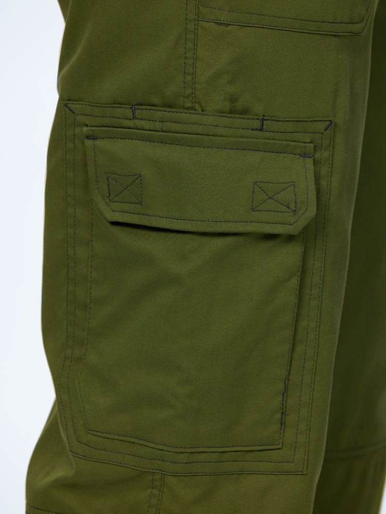Man wearing an Epic by MedWorks Men's Button Front Scrub Pant in olive with 1 double cargo pocket on wearer's right side.