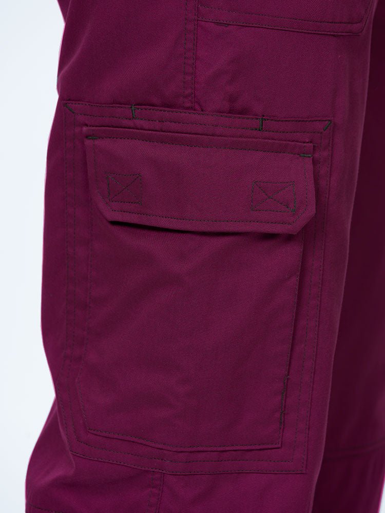 Man wearing an Epic by MedWorks Men's Button Front Scrub Pant in wine with 1 double cargo pocket on wearer's right side.