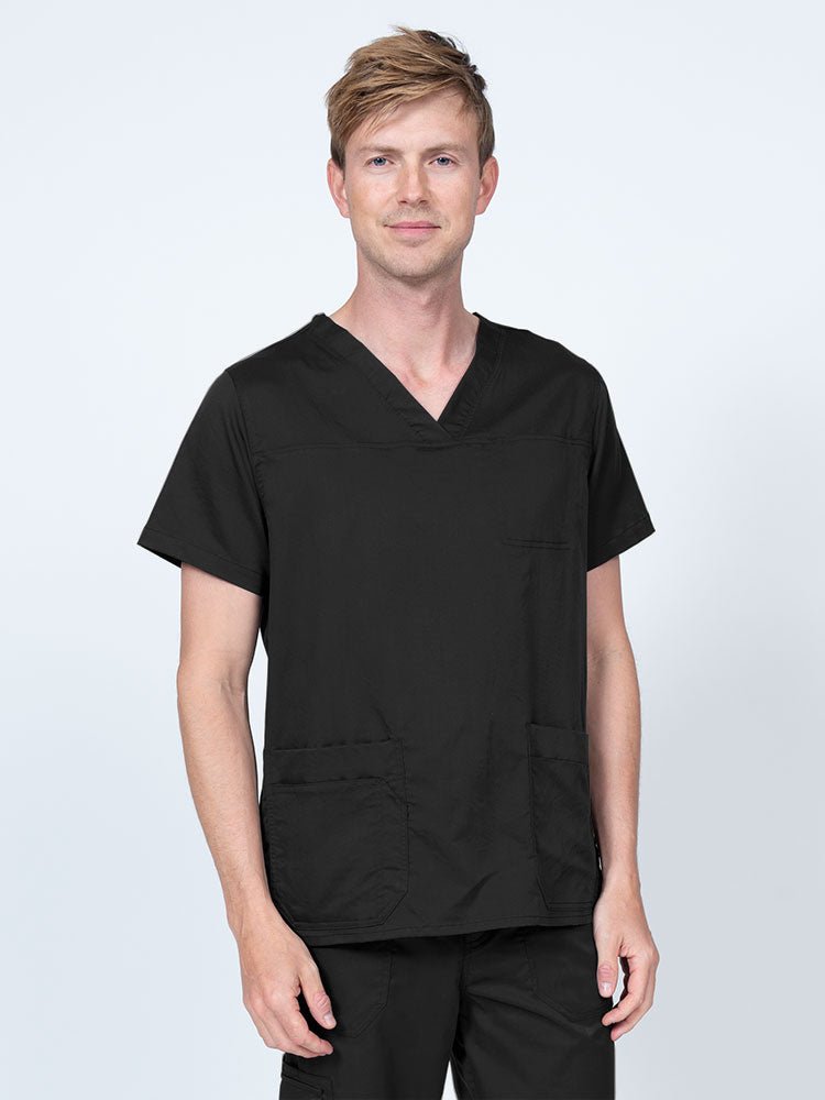 Male healthcare professional wearing an Epic by MedWorks Men's Scrub Top in black with 2 front patch pockets and 1 exterior cell phone pocket on the wearer's right side.