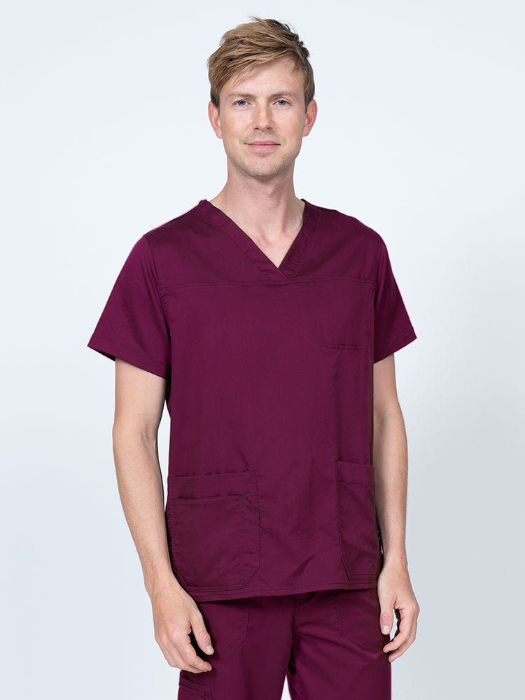 Male healthcare professional wearing an Epic by MedWorks Men's Scrub Top in wine with 2 front patch pockets and 1 exterior cell phone pocket on the wearer's right side.