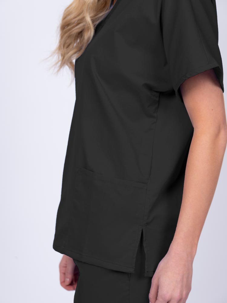 Young female healthcare worker wearing an Epic by MedWorks Unisex V-Neck Scrub Top in black with side slits for mobility & flair.