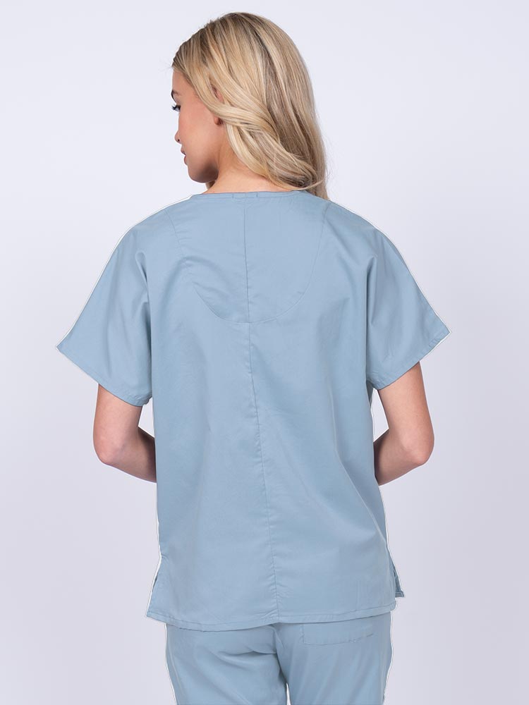 Woman wearing an Epic by MedWorks Unisex V-Neck Scrub Top in blue fog with a center back length of 27.5".