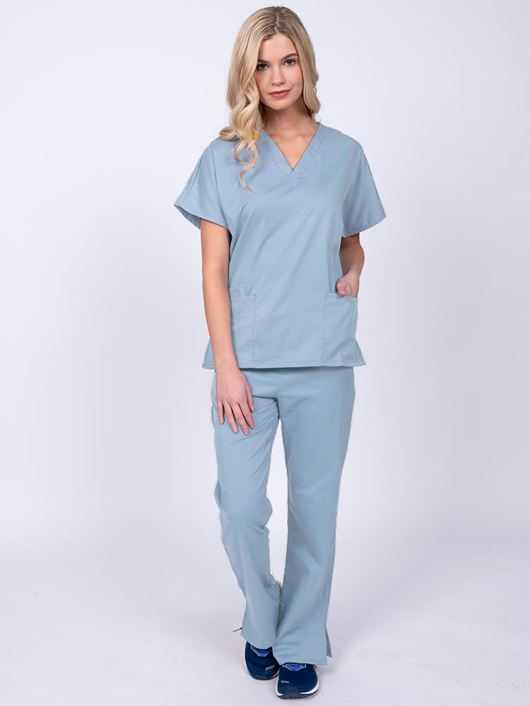 Young woman wearing an Epic by MedWorks Unisex Scrub Top in blue fog featuring a V-neckline & short sleeves.