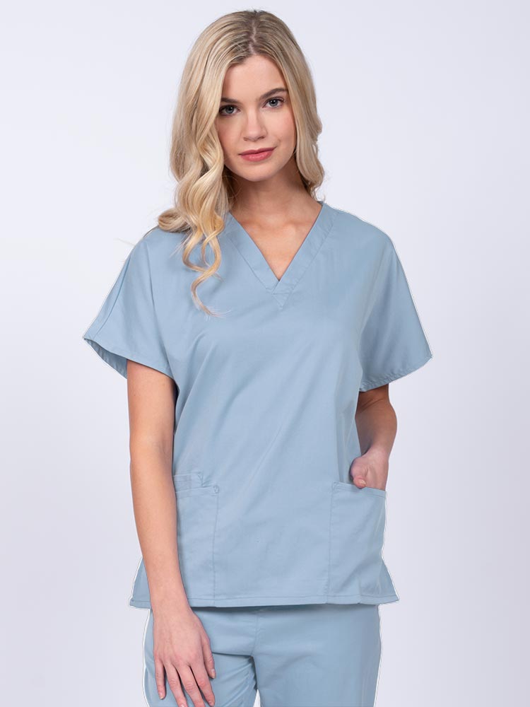 Young nurse wearing an Epic by MedWorks Unisex V-Neck Scrub Top in blue fog with a unique, easy care fabric made of 77% polyester, 21% Viscose and 2% Spandex.