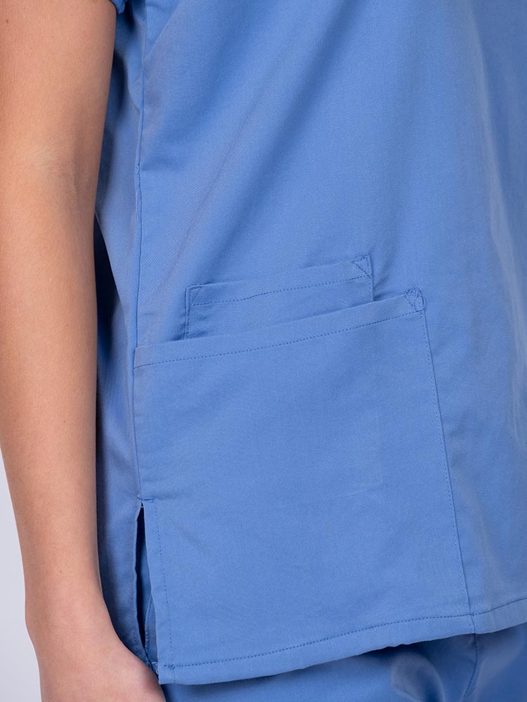 Woman wearing an Epic by MedWorks Unisex V-Neck Scrub Top in ceil with 2 patch pockets and a cell phone pocket.