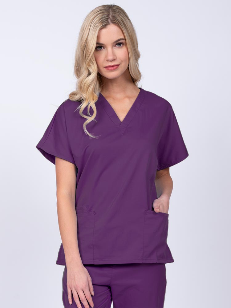 Young nurse wearing an Epic by MedWorks Unisex V-Neck Scrub Top in eggplant with a unique, easy care fabric made of 77% polyester, 21% Viscose and 2% Spandex.