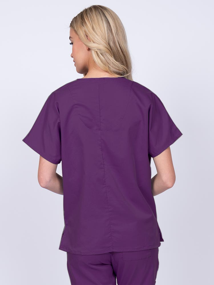 Woman wearing an Epic by MedWorks Unisex V-Neck Scrub Top in eggplant with a center back length of 27.5".