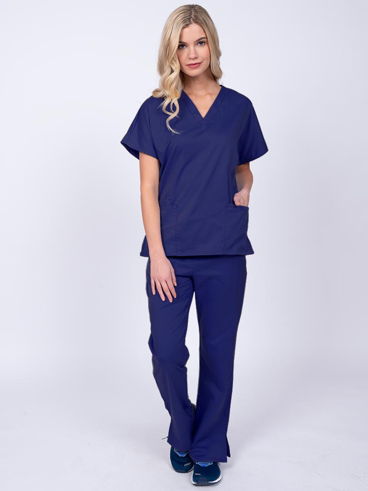 Young woman wearing an Epic by MedWorks Unisex Scrub Top in navy featuring a V-neckline & short sleeves.
