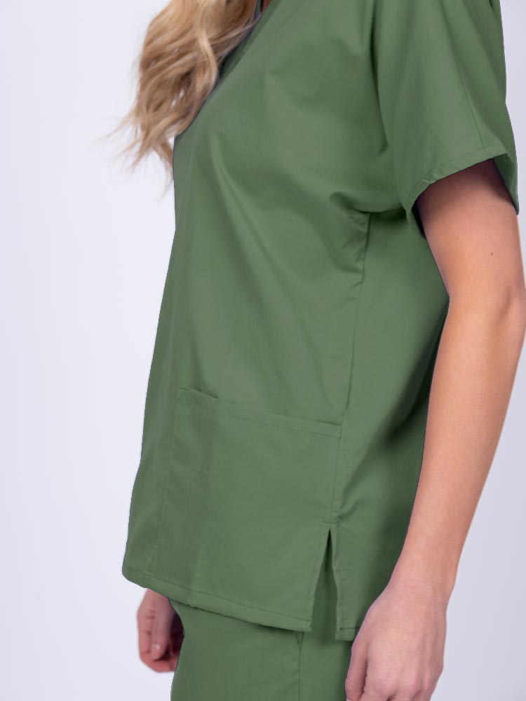 Young female healthcare worker wearing an Epic by MedWorks Unisex V-Neck Scrub Top in olive with side slits for mobility & flair.