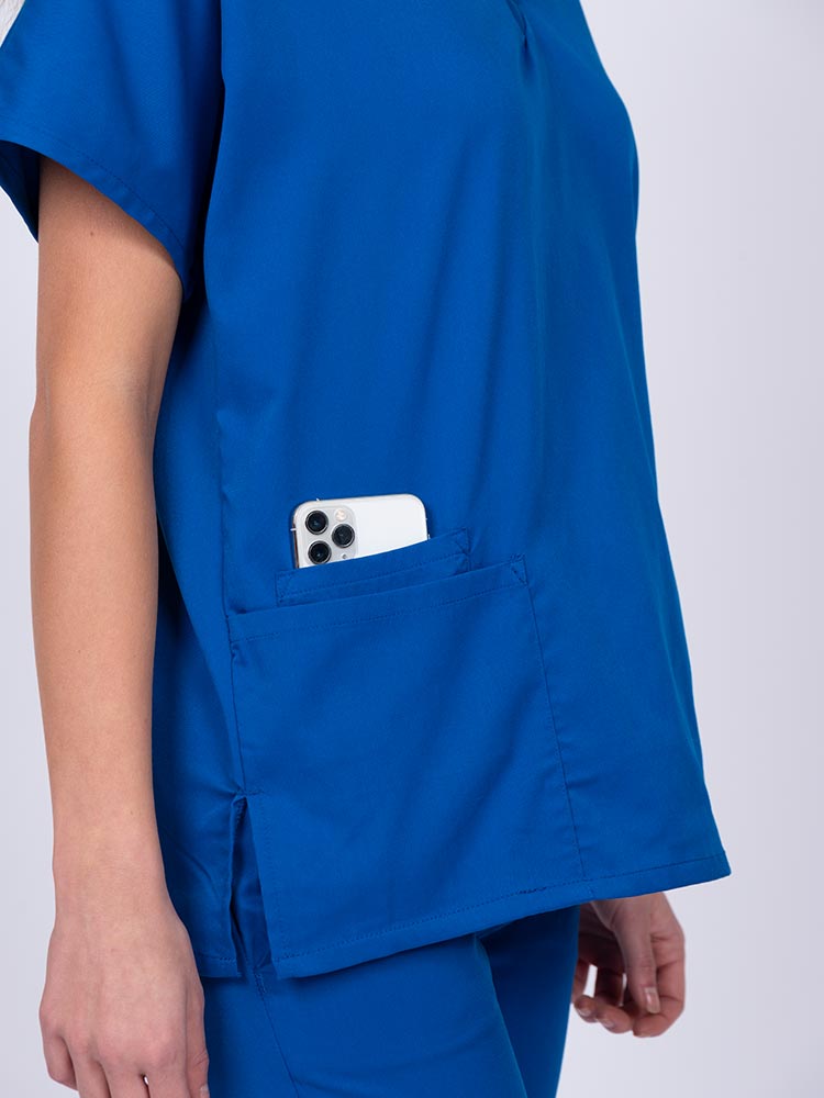Young female healthcare worker wearing an Epic by MedWorks Unisex V-Neck Scrub Top in royal with side slits for mobility & flair.