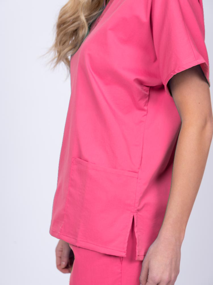 Young female healthcare worker wearing an Epic by MedWorks Unisex V-Neck Scrub Top in shocking pink with side slits for mobility & flair.