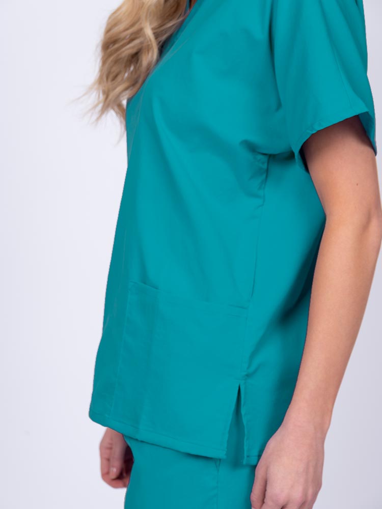 Young female healthcare worker wearing an Epic by MedWorks Unisex V-Neck Scrub Top in teal with side slits for mobility & flair.