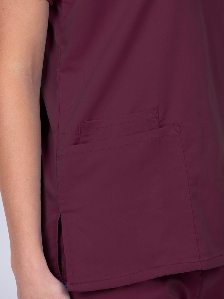 Woman wearing an Epic by MedWorks Unisex V-Neck Scrub Top in wine with 2 patch pockets and a cell phone pocket.
