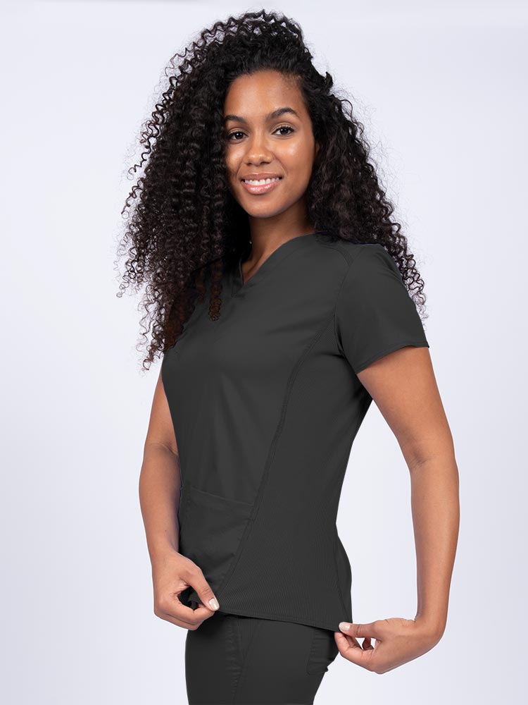 Nurse wearing an Epic by MedWorks Women's Blessed Scrub Top in black with stylish seaming throughout.