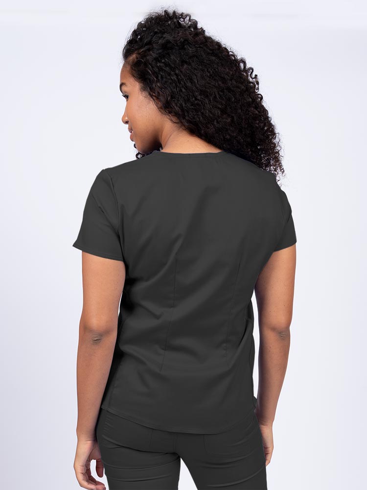 Woman wearing an Epic by MedWorks Women's Blessed Scrub Top in black with a pleated back for a flattering fit.