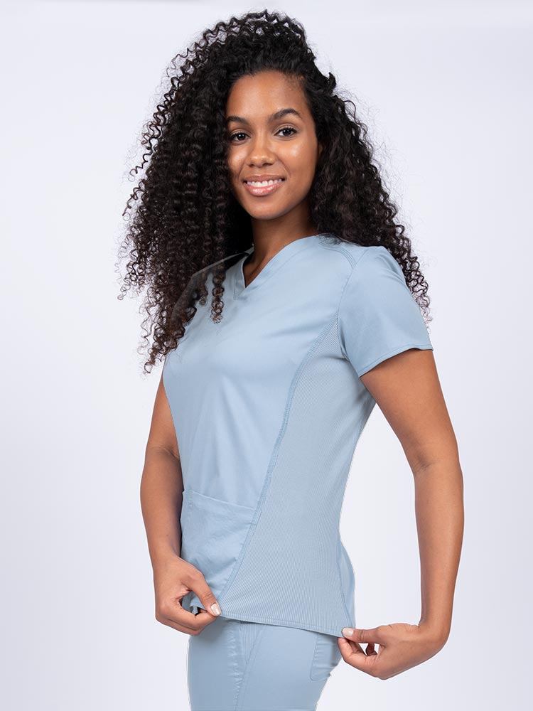 Nurse wearing an Epic by MedWorks Women's Blessed Scrub Top in blue fog with stylish seaming throughout.