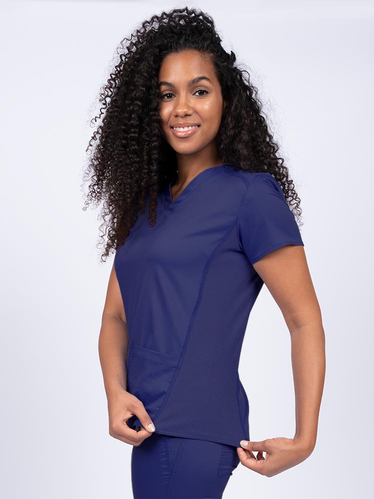 Nurse wearing an Epic by MedWorks Women's Blessed Scrub Top in navy with stylish seaming throughout.