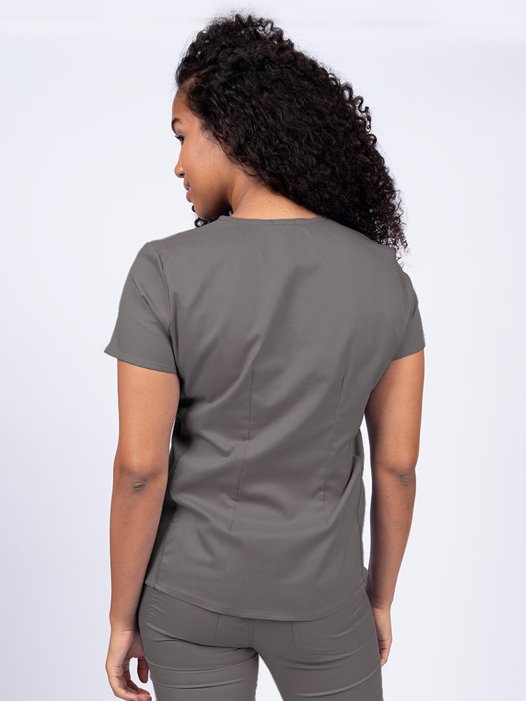 Woman wearing an Epic by MedWorks Women's Blessed Scrub Top in pewter with a pleated back for a flattering fit.