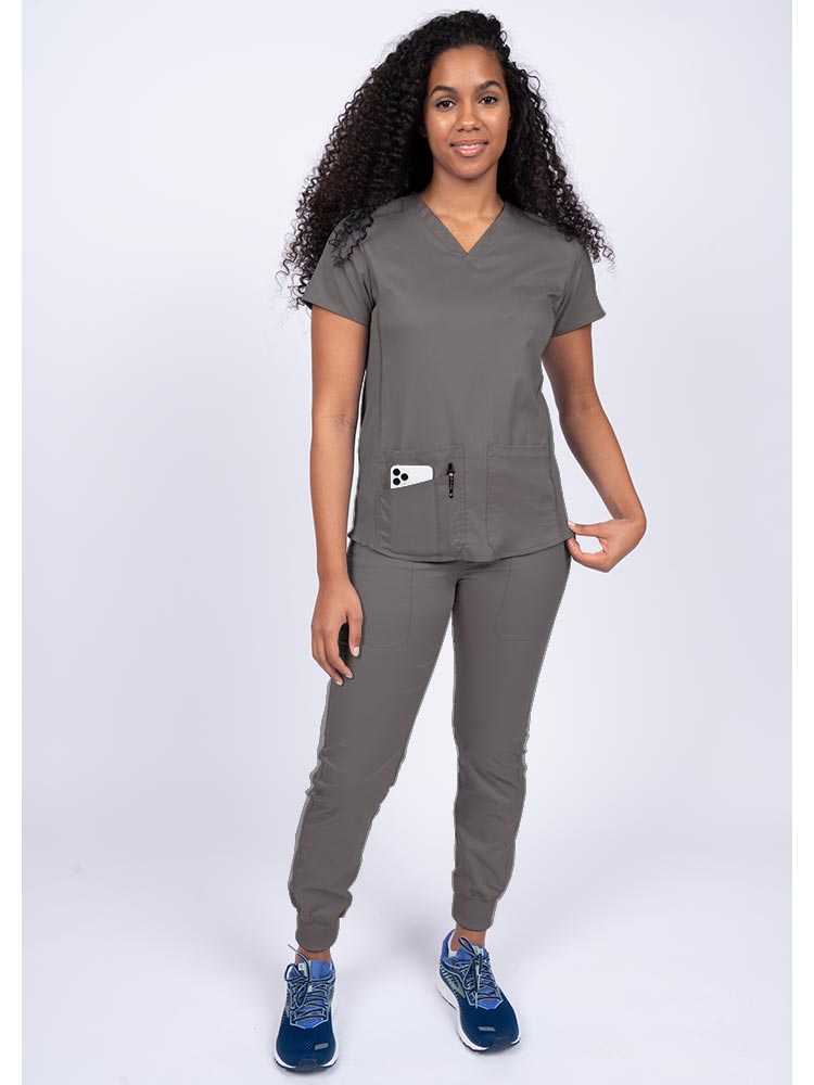 Young female healthcare professional wearing an Epic by MedWorks Women's Blessed Scrub Top in pewter with a total of 3 pockets & 1 pen slot.