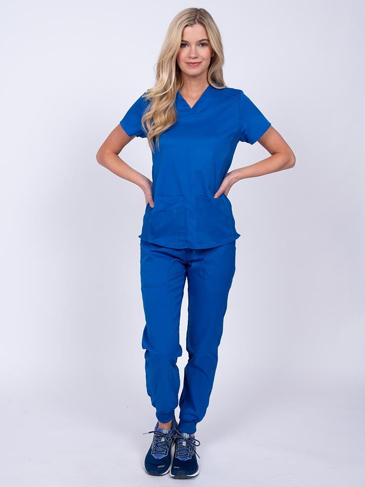 Young female healthcare professional wearing an Epic by MedWorks Women's Blessed Scrub Top in royal with a total of 3 pockets & 1 pen slot